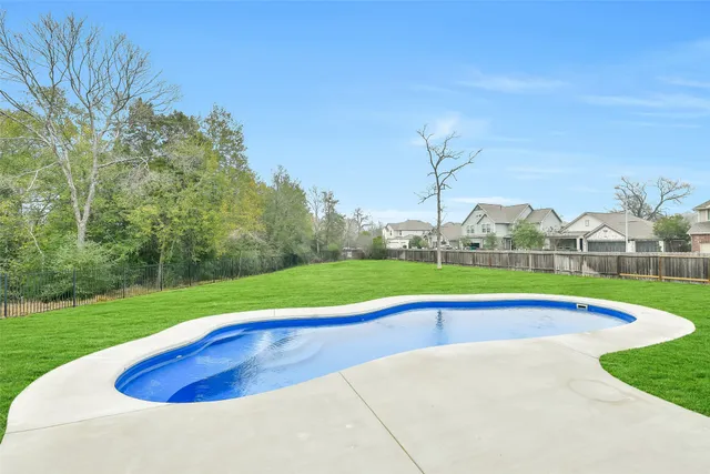 a view of pool with a big yard and large trees
