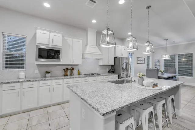 a kitchen with kitchen island granite countertop a sink a counter space appliances and cabinets