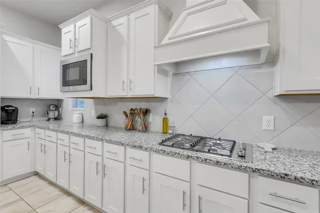 a kitchen with granite countertop white cabinets and stainless steel appliances
