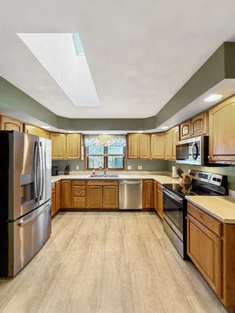 a kitchen with stainless steel appliances a stove top oven a sink a refrigerator and white cabinets