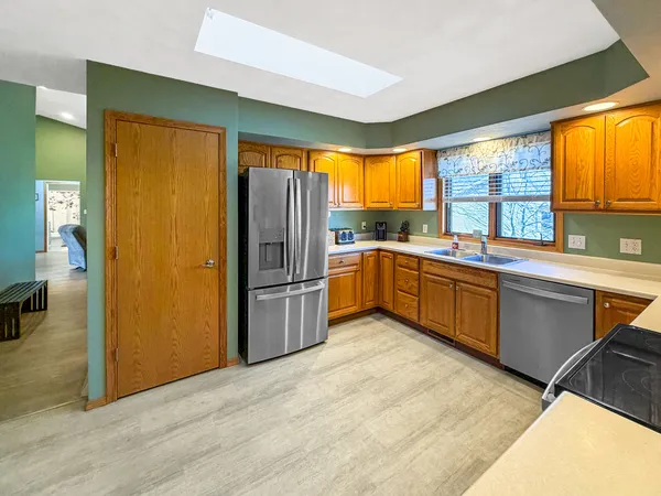 a kitchen with a sink appliances cabinets and a large window