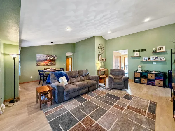 a living room with furniture and a flat screen tv with kitchen view