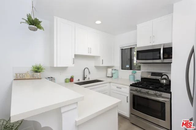 a kitchen with stainless steel appliances a sink a stove a microwave a sink a refrigerator and cabinets