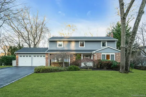 a front view of a house with a garden and trees