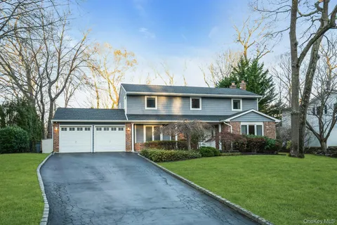 a view of house with a big yard and large trees