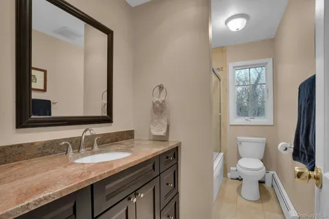 a bathroom with a granite countertop toilet sink and mirror