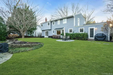 a front view of a house with a garden and trees