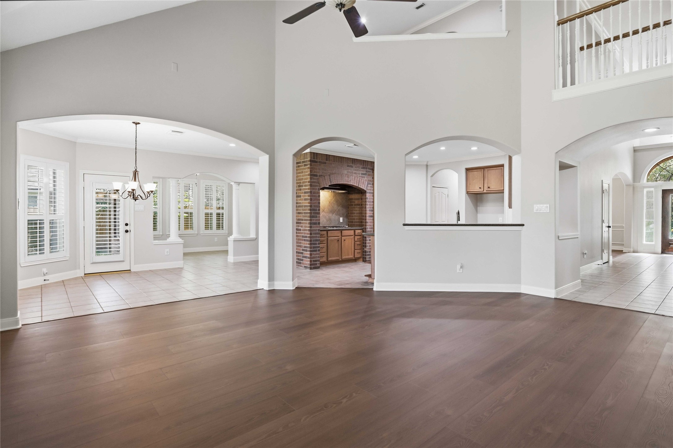 3303 Raleigh Row Missouri City, TX 77459 - Photo 15 of 50 Spacious living area with elegant hardwood floors, high ceilings, and arched entryways leading to a bright Breakfast space , Sunroom and a cozy kitchen with brick accents and bar seating arch.