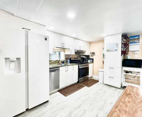 a kitchen with stainless steel appliances a refrigerator sink and white cabinets