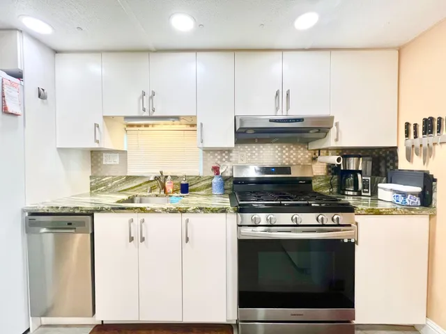 a kitchen with stainless steel appliances granite countertop a stove and a white cabinets