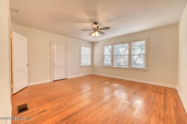 an empty room with windows and ceiling fan