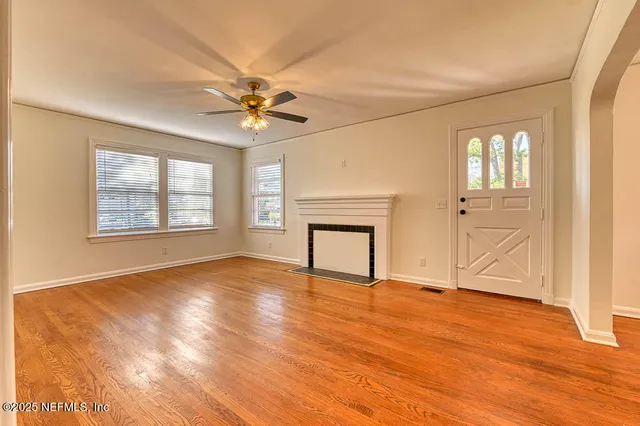 a view of an empty room with window and wooden floor