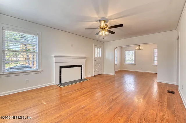 a view of an empty room with a window and wooden floor