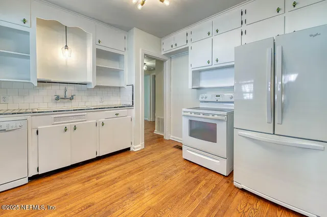 a kitchen with stainless steel appliances white cabinets and wooden floors