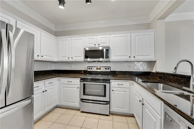 a kitchen with white cabinets stainless steel appliances and a sink