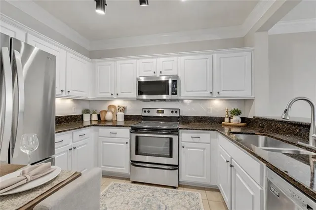 a kitchen with granite countertop white cabinets and stainless steel appliances