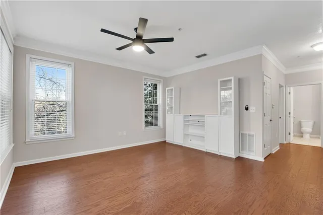 a view of an empty room with a window and wooden floor