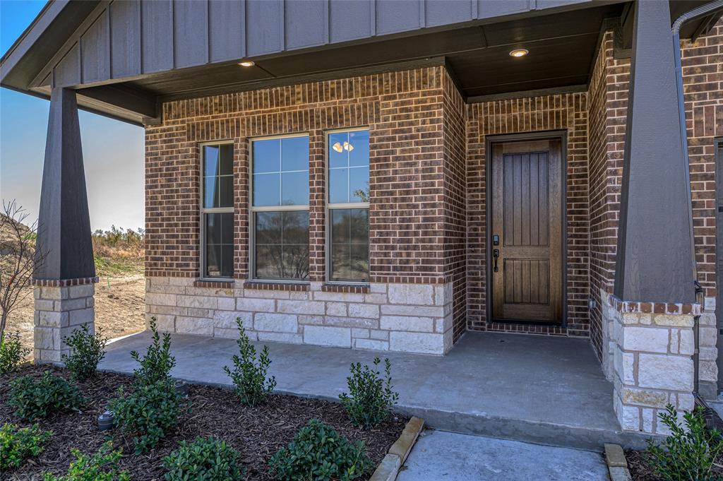 613 Brazos Drive Van Alstyne, TX 75495 - Photo 5 of 29 View of exterior entry featuring board and batten siding, covered porch, stone siding, and brick siding