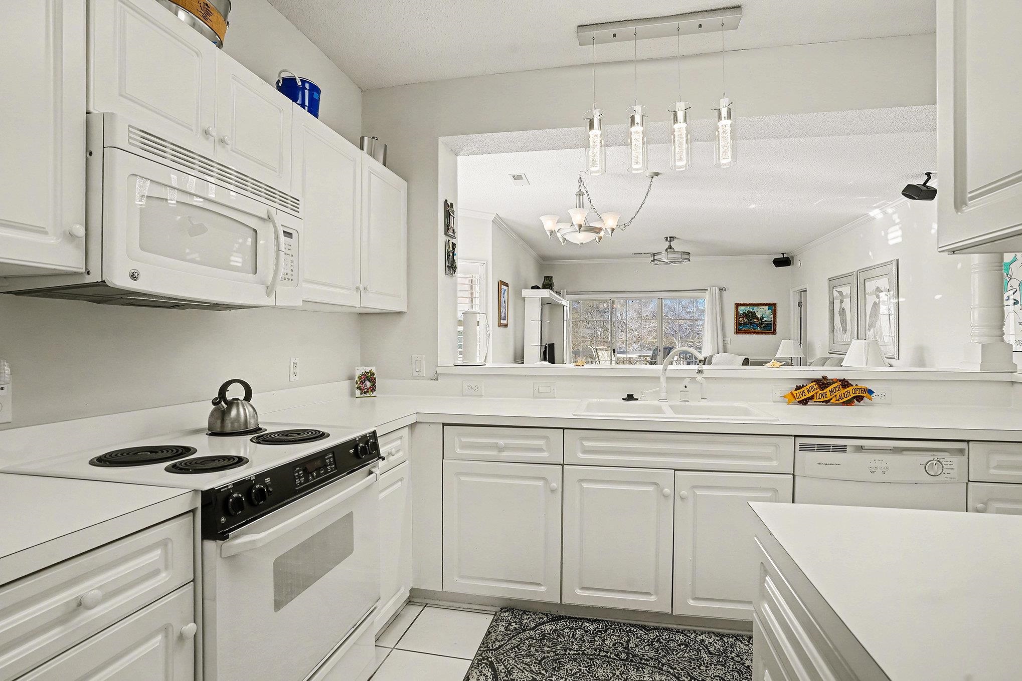 4429 Turtle Lane, Unit 3A Little River, SC 29566 - Photo 10 of 31 Kitchen with white appliances, light countertops, white cabinets, hanging light fixtures, and light tile patterned flooring