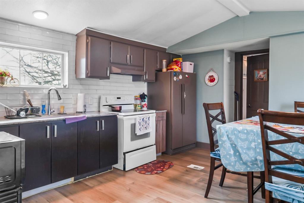 244 Smith Circle Point, TX 75472 - Photo 5 of 15 Kitchen with white range with electric cooktop, decorative backsplash, light wood finished floors, freestanding refrigerator, and dark wood finish cabinetry