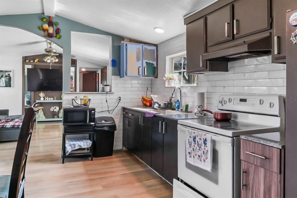 244 Smith Circle Point, TX 75472 - Photo 6 of 15 Kitchen with white range with electric stovetop, light wood finished floors, lofted ceiling, black microwave, and decorative backsplash
