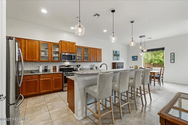 a kitchen with stainless steel appliances granite countertop a stove top oven a sink a dining table and chairs with wooden floor