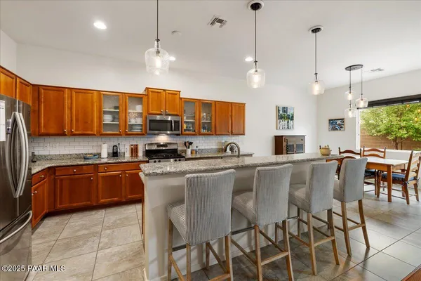 a large kitchen with stainless steel appliances granite countertop a stove a sink dishwasher a refrigerator with a dining table and chairs with wooden floor