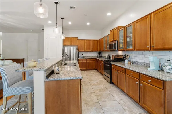 a kitchen with stainless steel appliances granite countertop a sink counter space cabinets and a stove