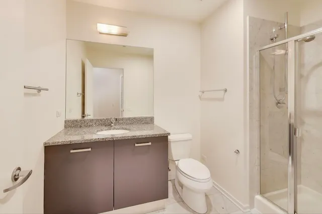 a bathroom with a granite countertop sink toilet and mirror
