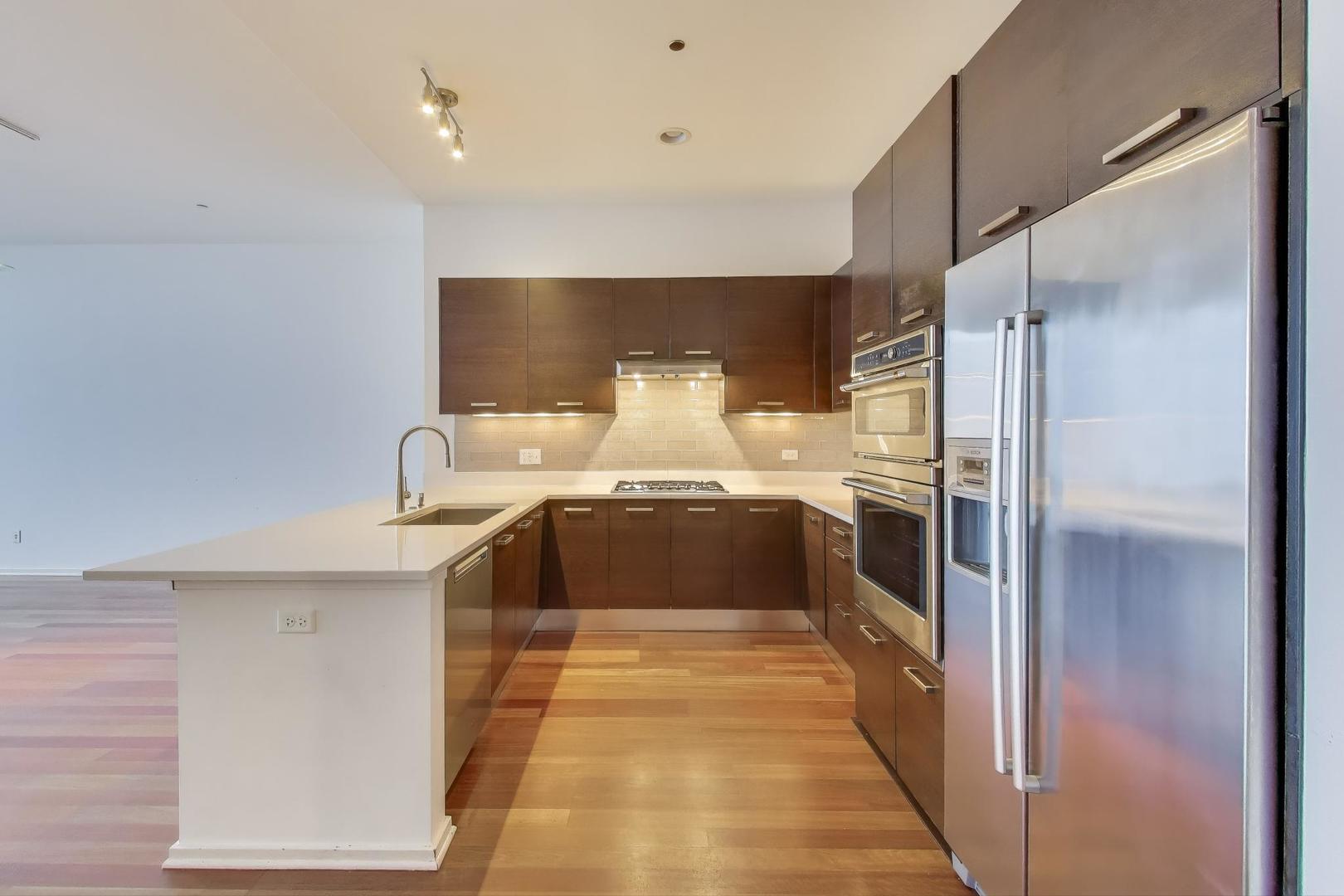 65 East Monroe Street, Unit 4405 Chicago, IL 60603 - Photo 5 of 27 a large white kitchen with stainless steel appliances a refrigerator and a stove