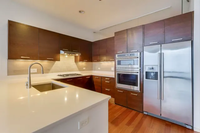 a kitchen with stainless steel appliances a refrigerator a sink a stove and cabinets