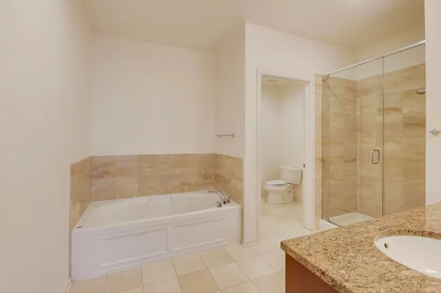 a bathroom with a granite countertop bathtub shower sink and toilet