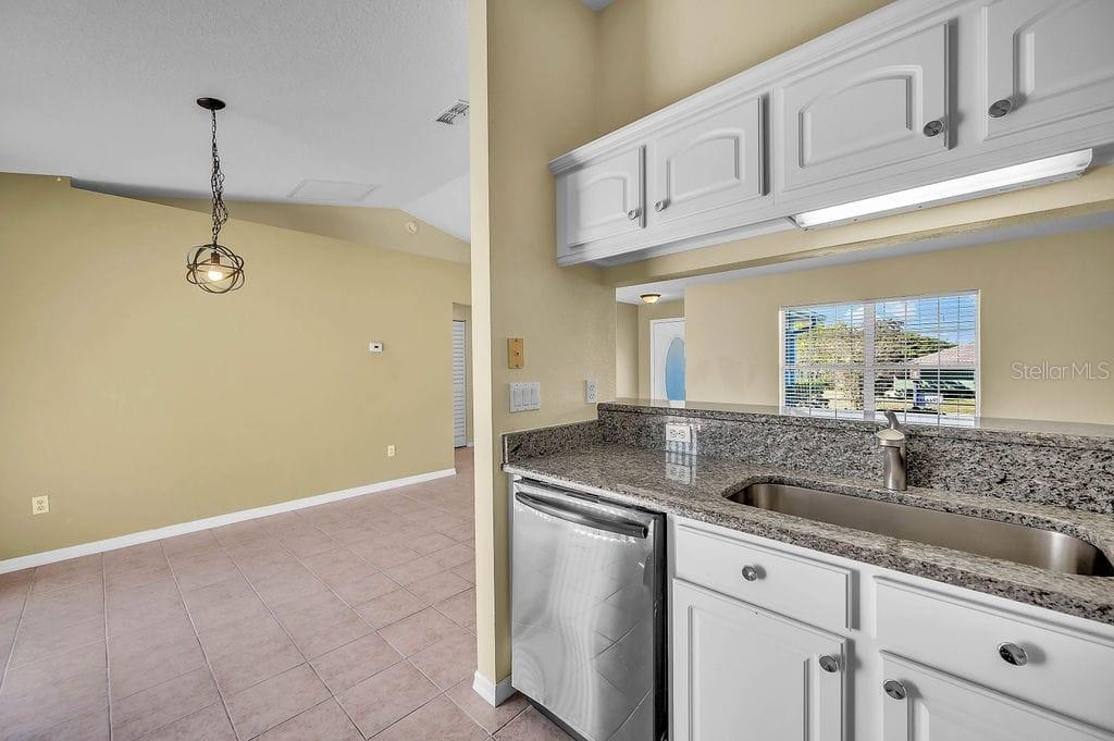 8695 Southwest 60th Circle Ocala, FL 34476 - Photo 8 of 19 a kitchen with stainless steel appliances granite countertop a sink a stove and white cabinets
