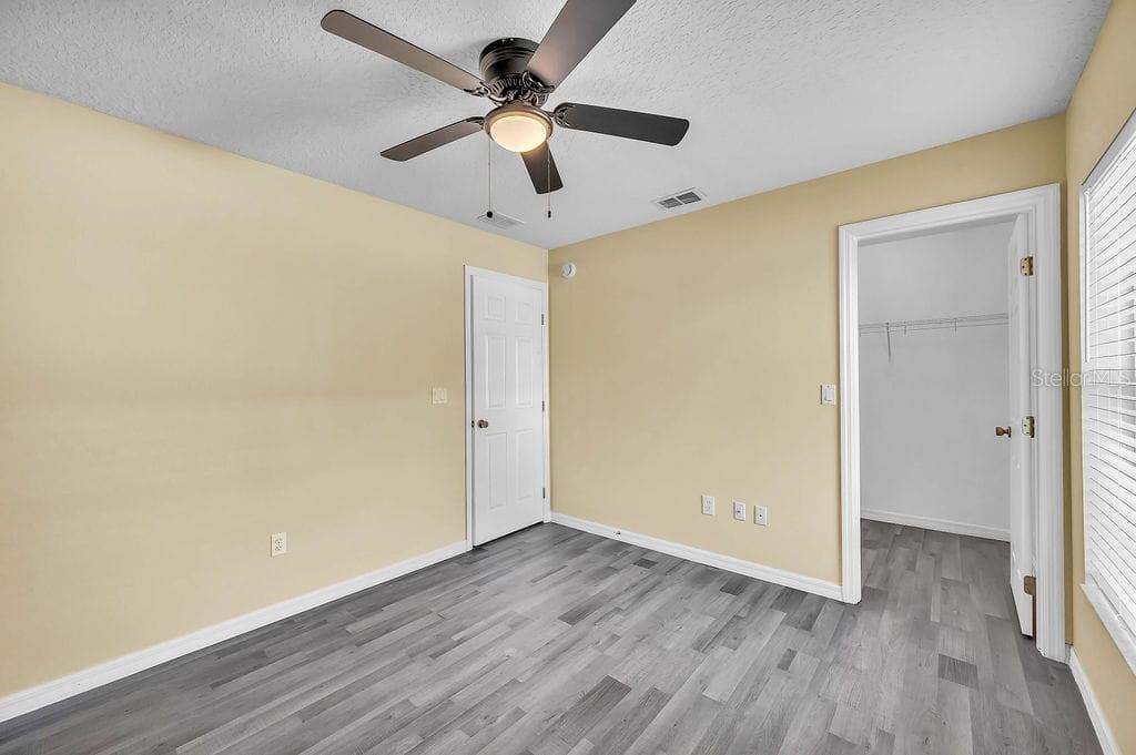 8695 Southwest 60th Circle Ocala, FL 34476 - Photo 10 of 19 an empty room with wooden floor ceiling fan and a ceiling fan