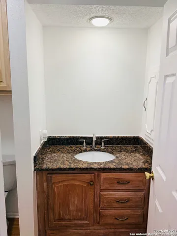 a bathroom with a granite countertop sink a toilet and bathtub