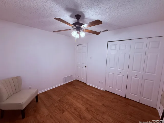 a view of an empty room with a ceiling fan and wooden floor