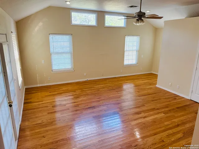 a view of an empty room with wooden floor and a window