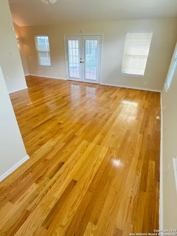 a view of an empty room with wooden floor and a window