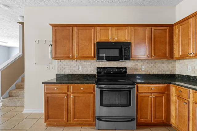 a kitchen with granite countertop a stove top oven microwave and cabinets