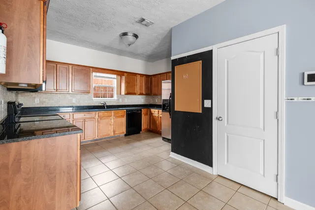 a kitchen with stainless steel appliances granite countertop a refrigerator and a stove top oven