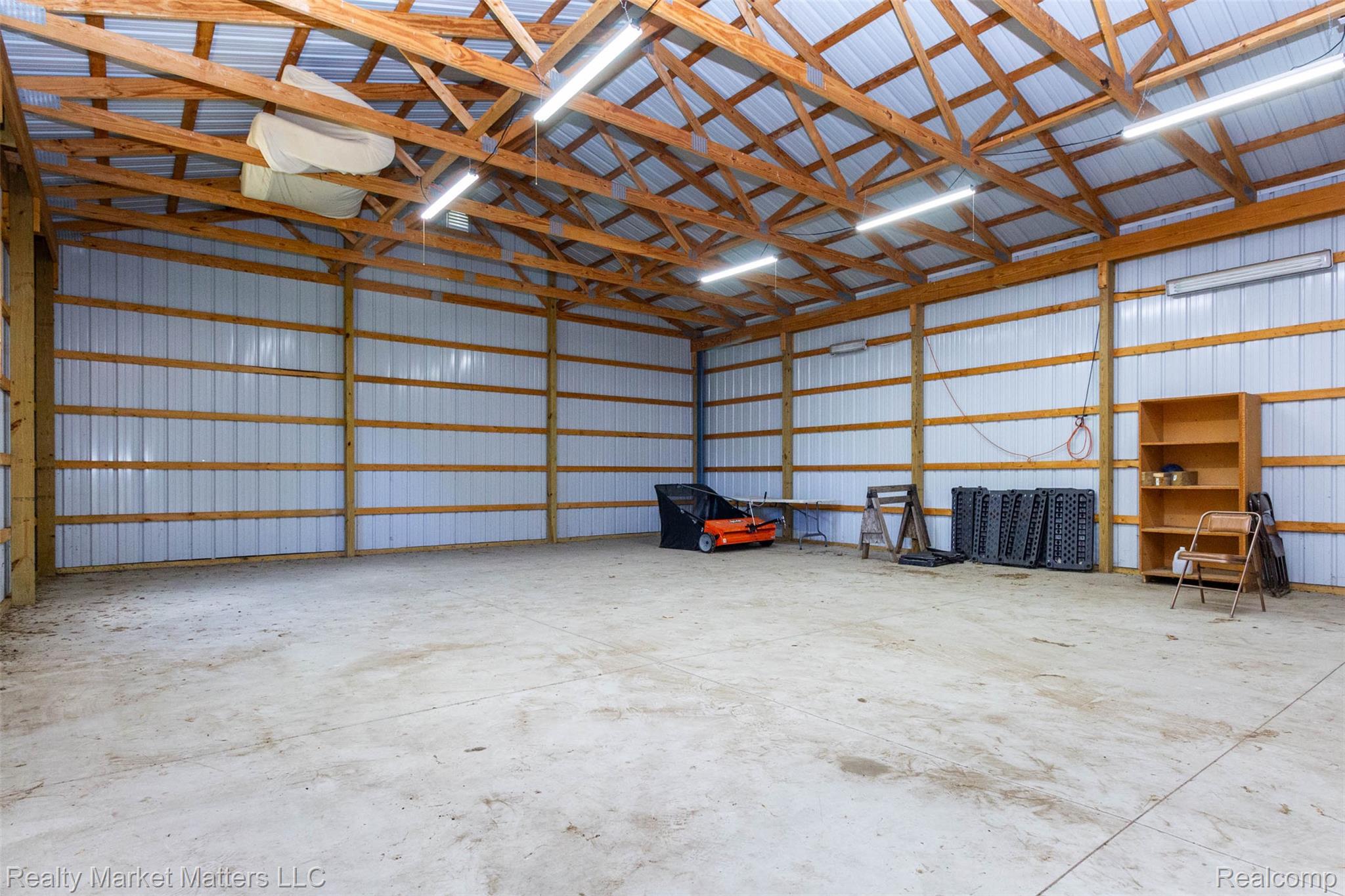 4951 Laur Road North Branch, MI 48461 - Photo 27 of 34 Spacious utility building featuring a high exposed timber beam ceiling, fluorescent lighting, corrugated metal walls, and a concrete floor