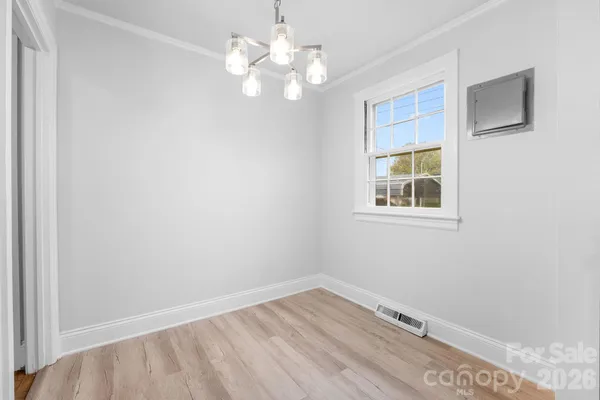 an empty room with a chandelier fan and windows