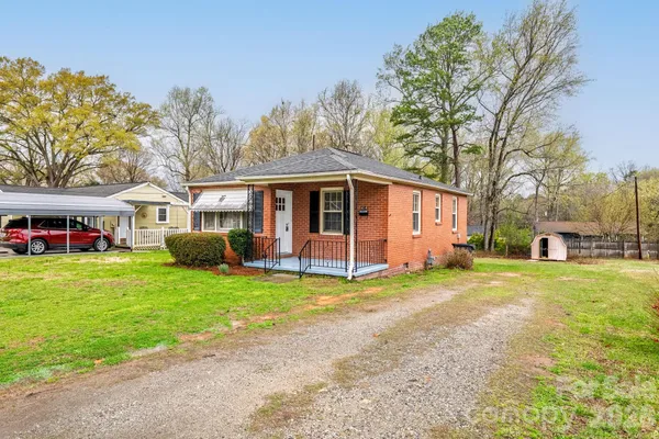 a view of a house with a yard and large tree