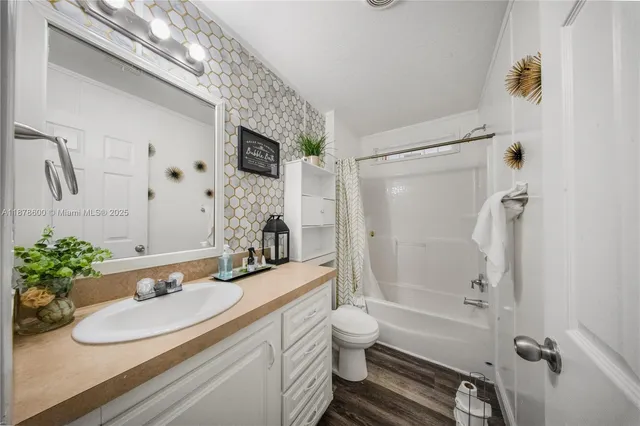 a bathroom with a granite countertop sink a toilet a mirror and shower