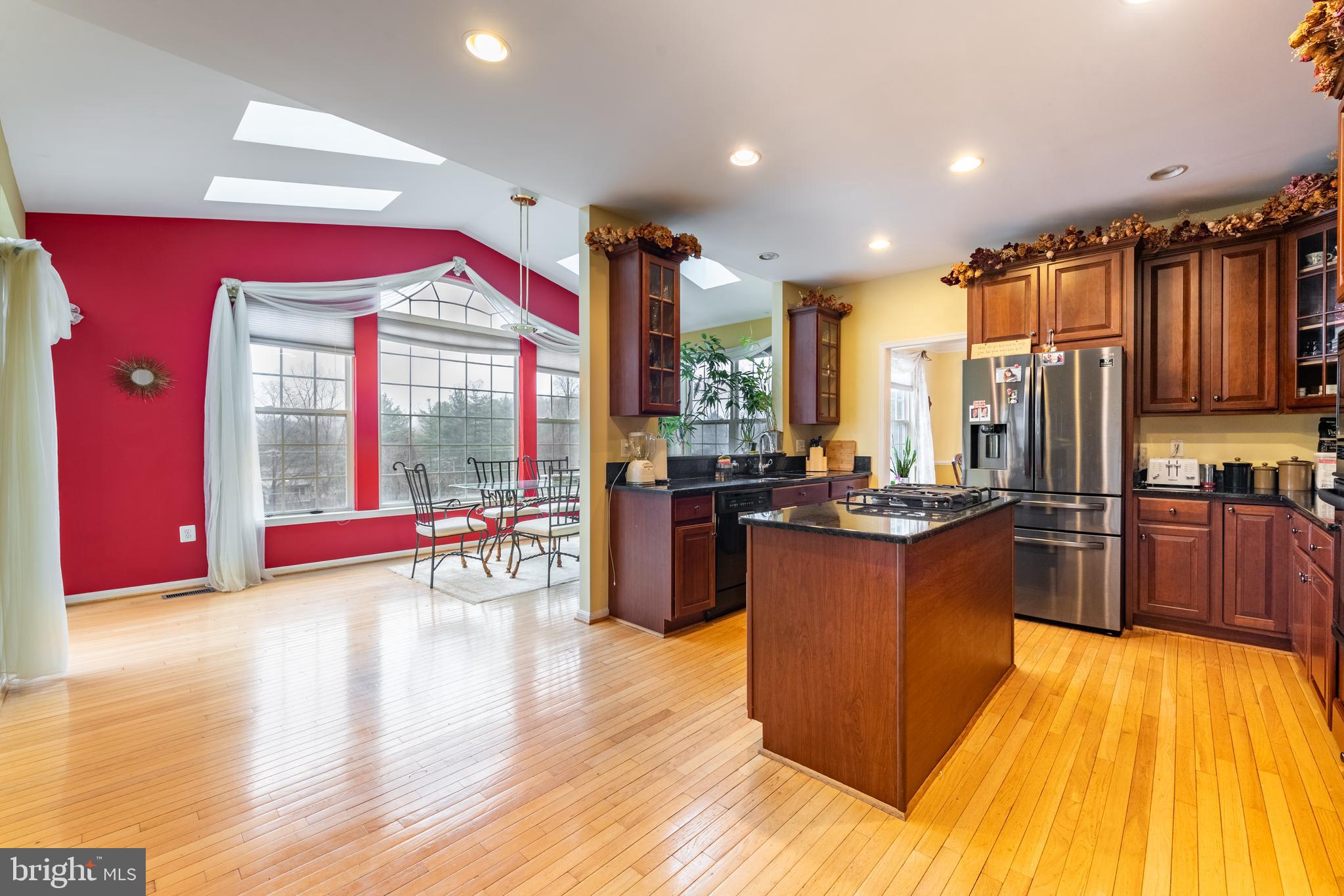 11 Manor Spring Court Silver Spring, MD 20906 - Photo 9 of 45 a large kitchen with stainless steel appliances granite countertop a large kitchen island a stove a refrigerator a dining table and chairs with wooden floor