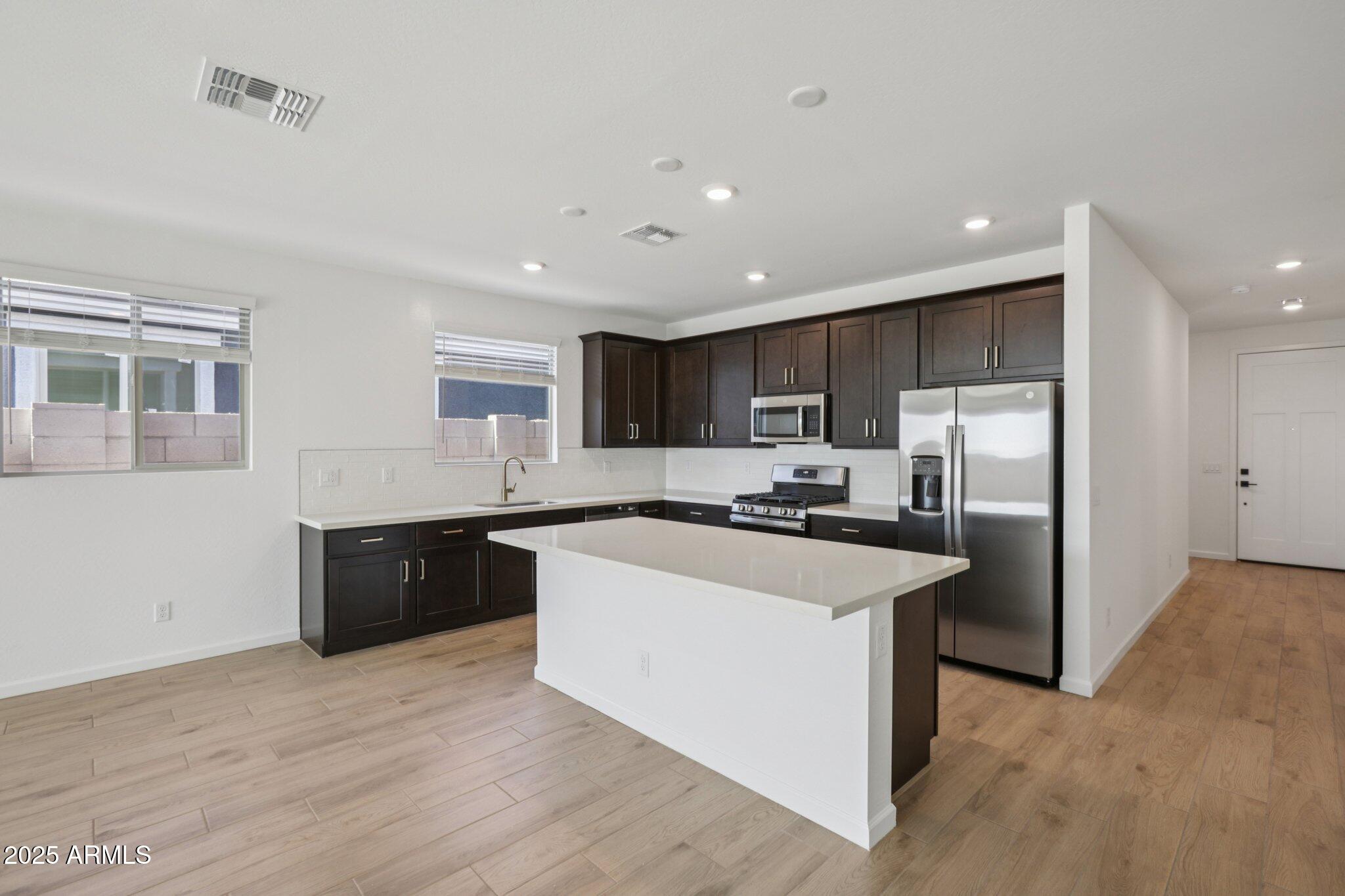 16219 West Bajada Road Surprise, AZ 85387 - Photo 9 of 43 a kitchen with stainless steel appliances granite countertop a refrigerator a sink dishwasher a stove with white cabinets and wooden floor