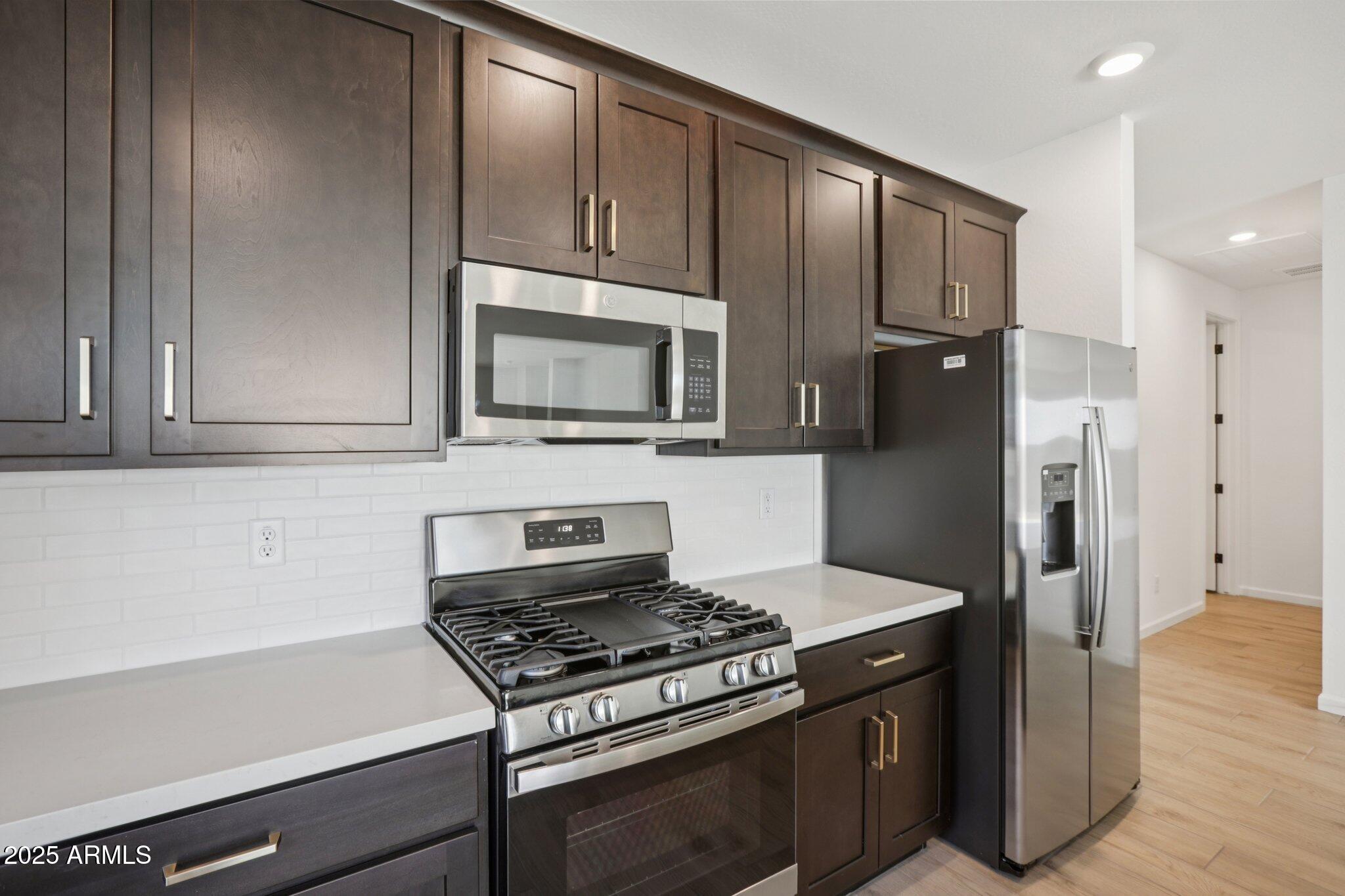 16219 West Bajada Road Surprise, AZ 85387 - Photo 10 of 43 a kitchen with granite countertop wooden cabinets and stainless steel appliances