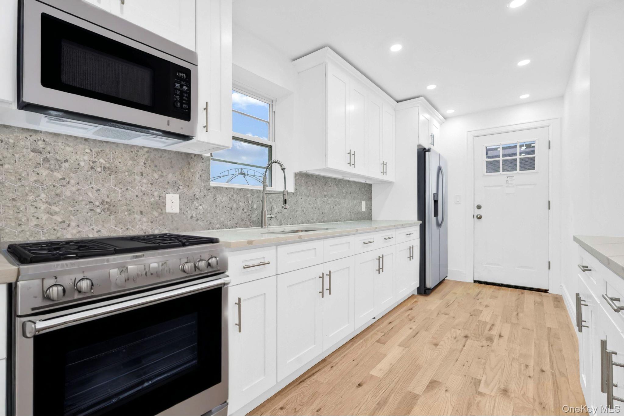 21432 112th Road Queens, NY 11429 - Photo 12 of 18 Kitchen featuring appliances with stainless steel finishes, white cabinets, light wood finished floors, and recessed lighting