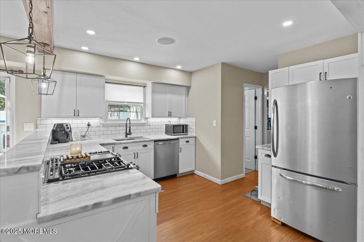 2110 Lanes Mill Road Brick, NJ 08724 - Photo 15 of 55 a kitchen with stainless steel appliances a refrigerator a sink dishwasher a stove and white cabinets with wooden floor
