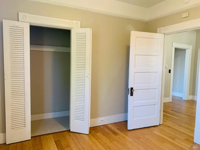 an empty room with wooden floor and closet